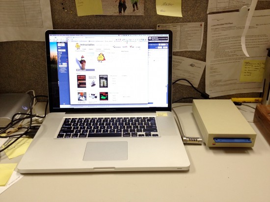 Apple's floppy drive, converted into an external HDD, against a MacBook Pro